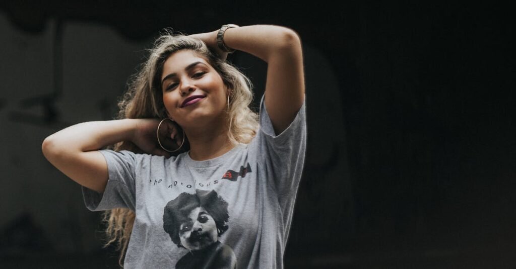 Queda de cabelo: 5 causas que podem estar por trás? 12 Young woman with blonde hair posing confidently in a The Notorious B.I.G. t-shirt against a dark background.