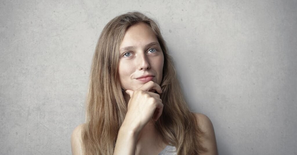 Queda de cabelo: 5 causas que podem estar por trás? 11 A thoughtful woman contemplates life in a simple portrait with a gray background.