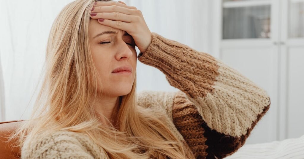 Close-up of a woman with a headache, hand on forehead, in a comfortable setting.