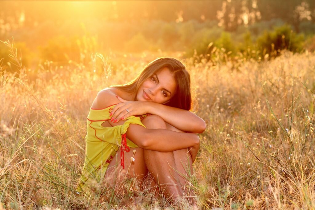 Mulher sentada ao sol num campo, em momento de tranquilidade, ilustrando o benefícios da exposição solar para o bem-estar – Vida em Equilíbrio