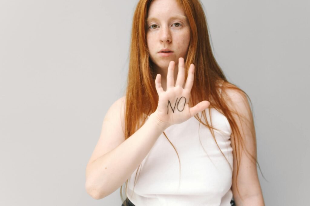 7 formas de dizer não sem culpa e com equilíbrio Mulher com a mão levantada com a palavra “NO” escrita, representando formas de dizer não e estabelecer limites de forma consciente para uma vida em equilíbrio