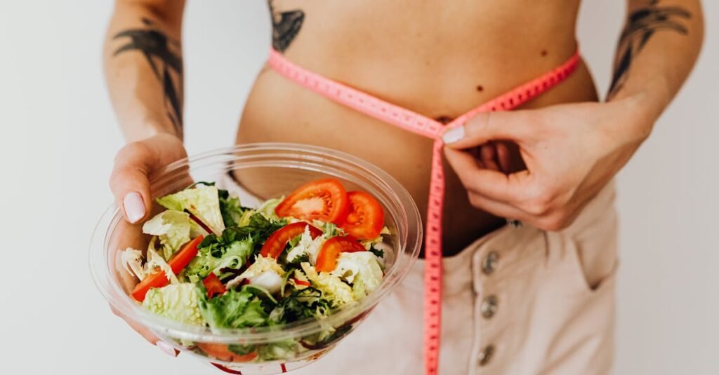Mulher a medir a cintura com fita métrica enquanto segura prato com salada, ilustrando mitos sobre nutrição e controlo alimentar