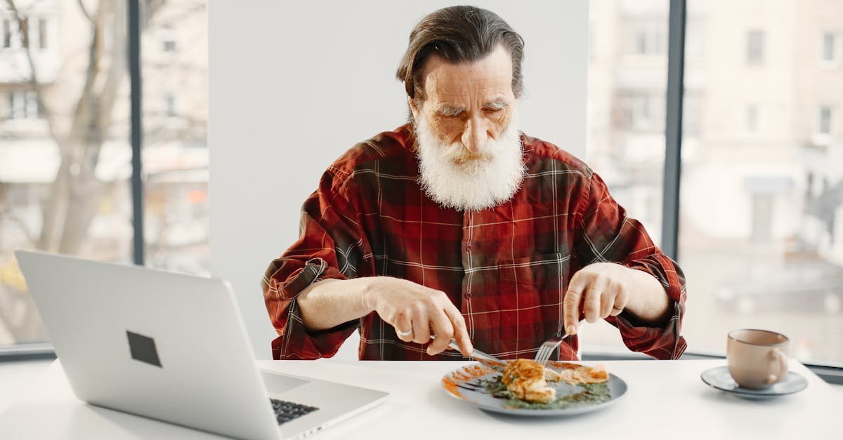 Ferro baixo sem anemia: 6 sinais a observar 1 Homem a comer sozinho enquanto trabalha no computador, possível ferro baixo sem anemia e sensação de cansaço