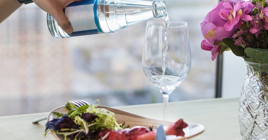 9 mitos sobre nutrição em que você ainda acredita 12 Água a ser servida num copo durante uma refeição, ilustrando hidratação e mitos sobre nutrição no contexto do Vida em Equilíbrio
